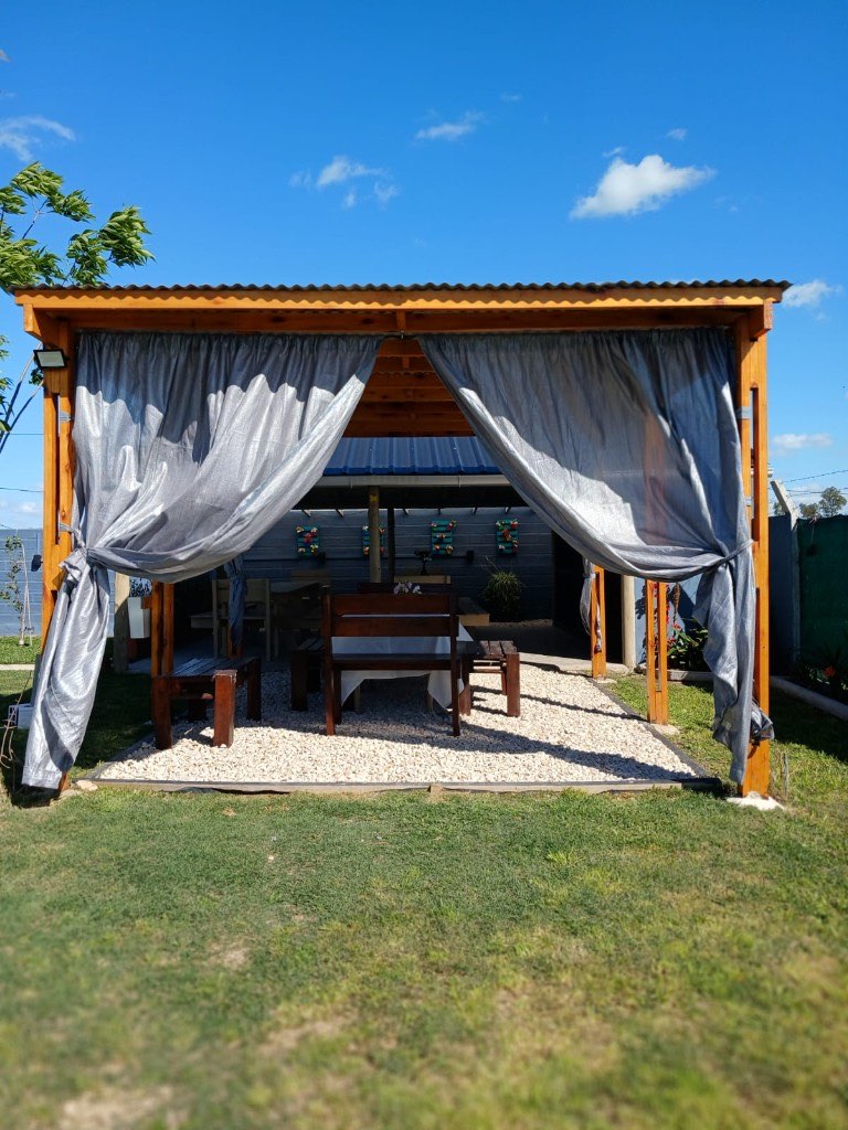 Pérgola de madera con cortinas grises en la quinta de Guernica