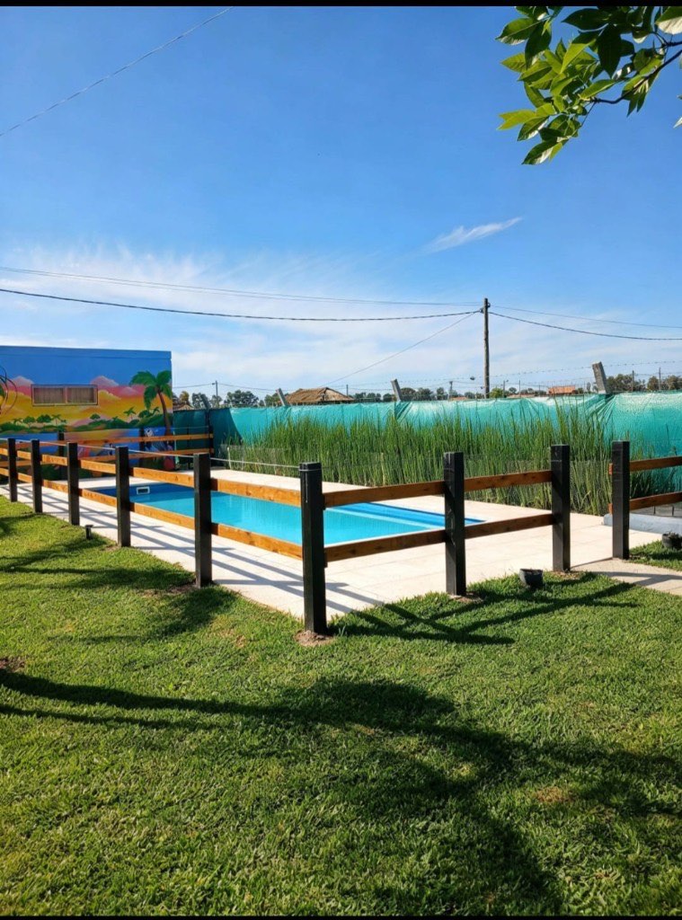 Pileta vista desde el parque, con cerco de madera