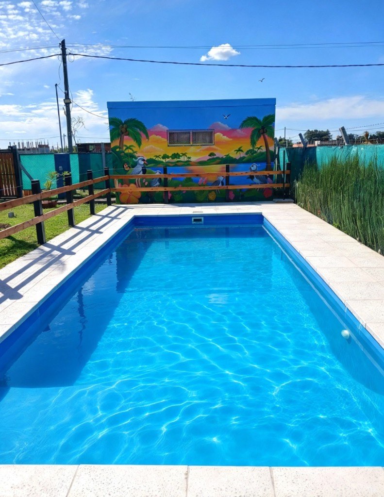 Piscina en Guernica con mural de palmeras y atardecer al fondo de la quinta